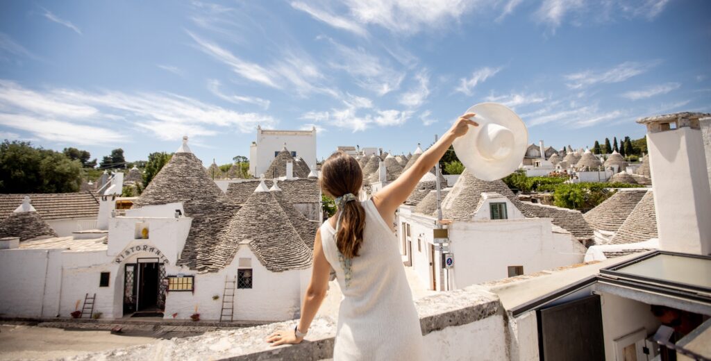 A young woman in a white dress and a hat during tourist visit in Alberobello, Italy